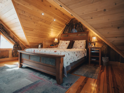 Bedroom in cabin with bed and wood floors and walls